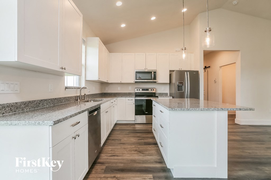 a large kitchen with white cabinets and granite counter tops
