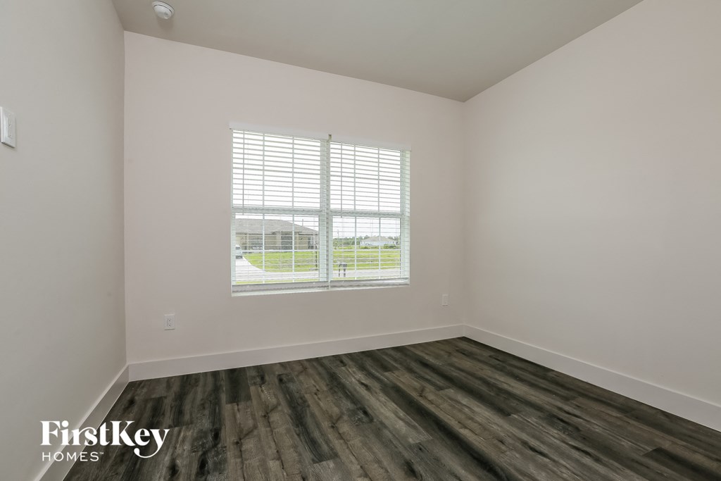 the living room of a home with wood flooring and a window
