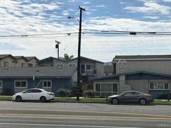 A white car is parked on the street in front of a house.