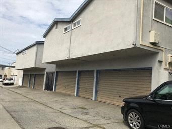 A black car is parked in front of a building with closed shutters.