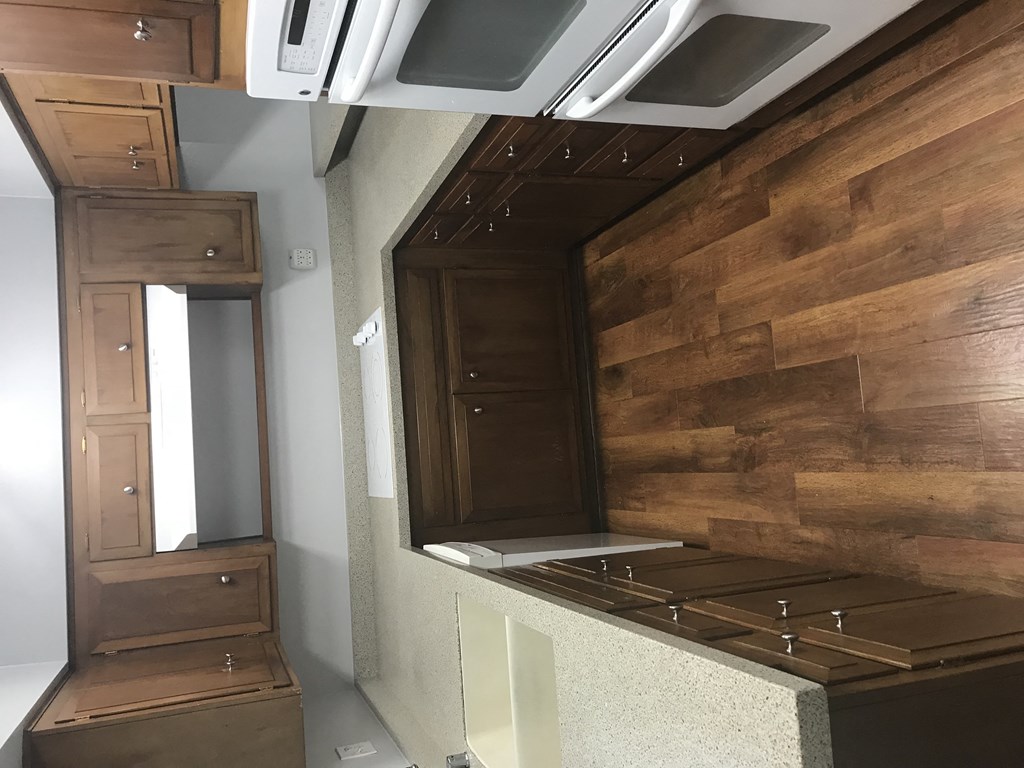 A kitchen with wooden cabinets and a stove top oven.
