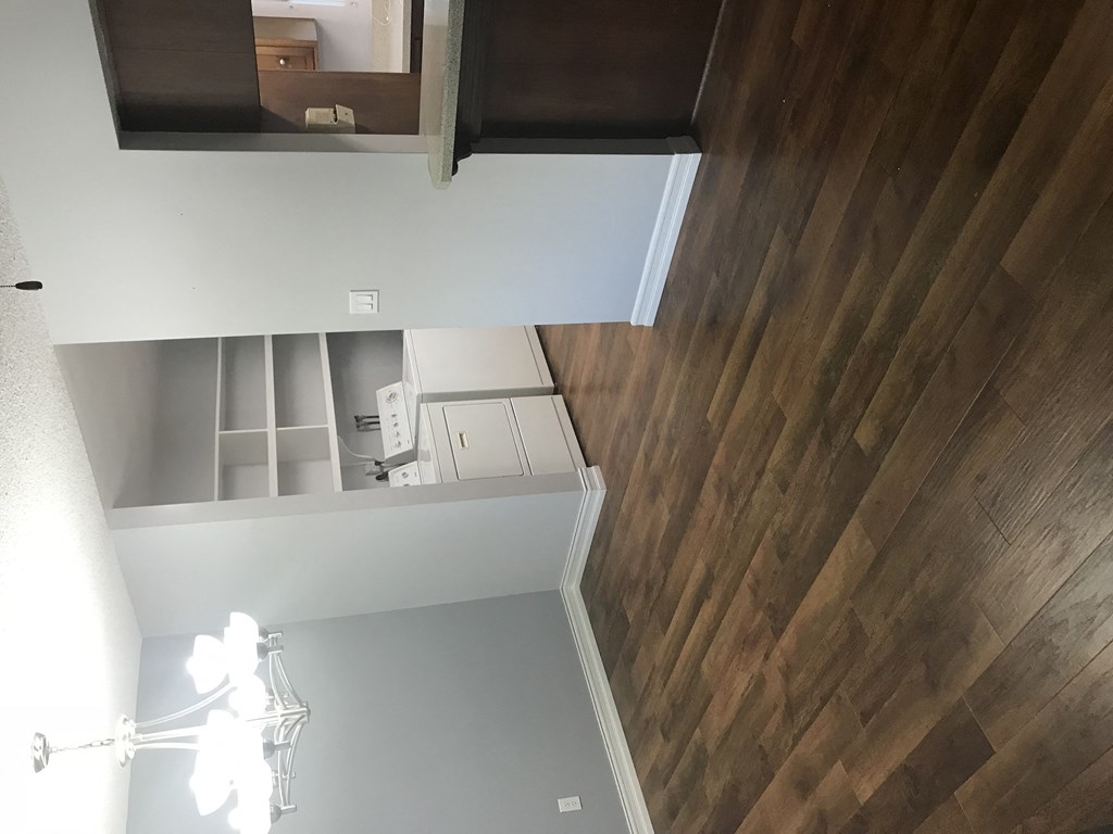 A chandelier hangs over a white table in a room with wood paneling on the walls.