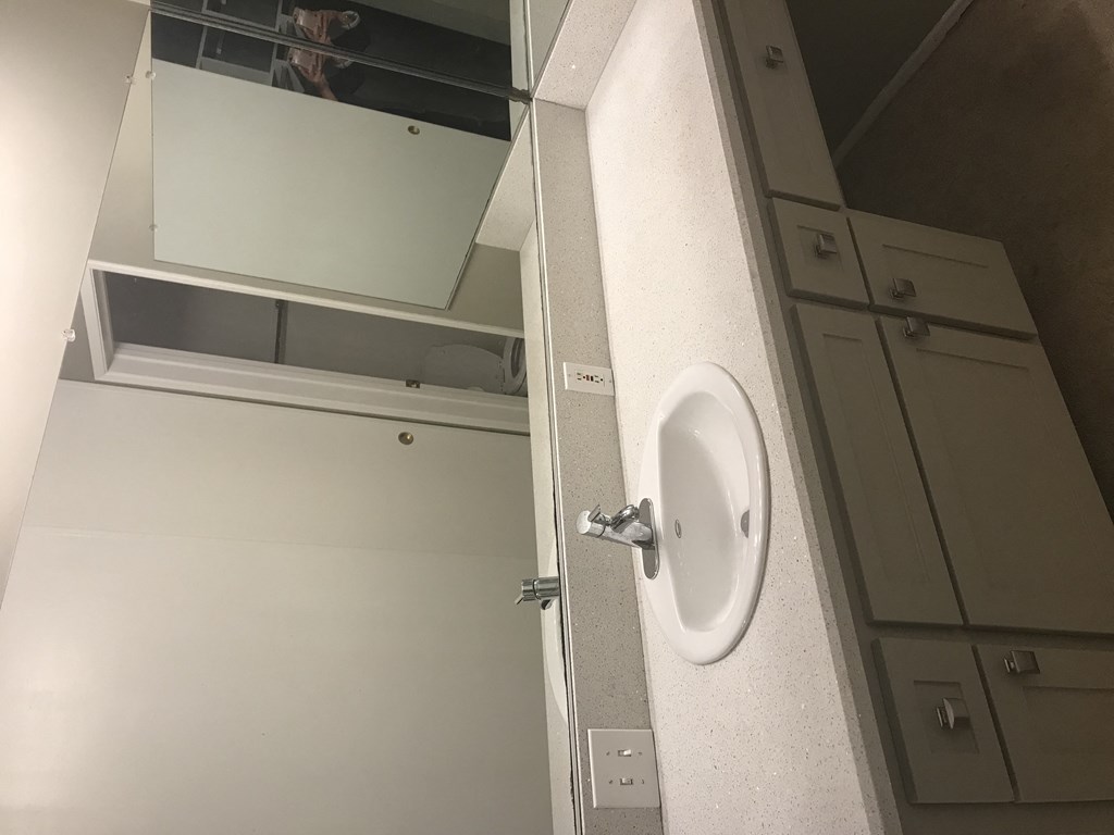 A white sink in a bathroom with a mirror above it.