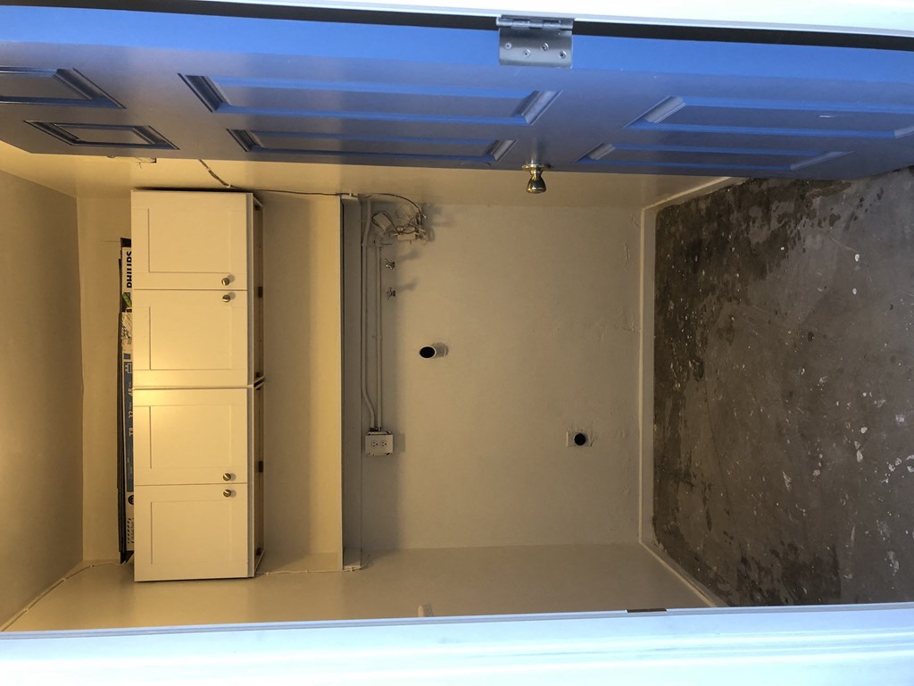 A white fridge in a room with a concrete wall.