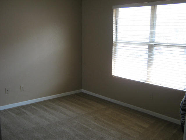 an empty room with a window and wooden floors