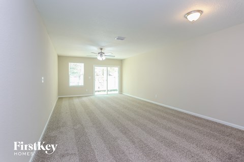 a spacious living room with carpet and a ceiling fan