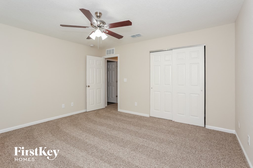 a spacious living room with carpet and a ceiling fan