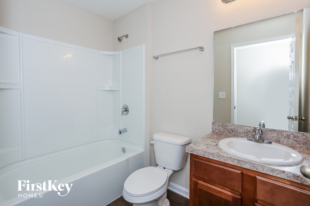 a bathroom with a toilet sink and tub and a mirror