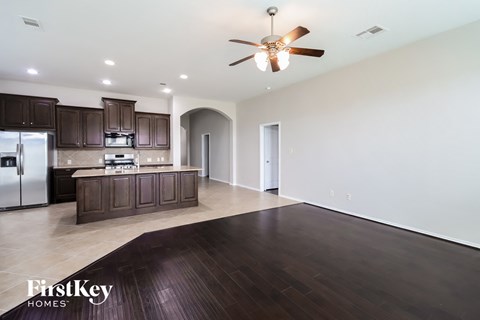 a kitchen and living room with wood flooring and a ceiling fan