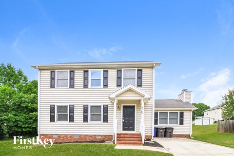 A two-story house with a front porch and a garage door.