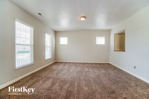 an empty living room with carpet and windows