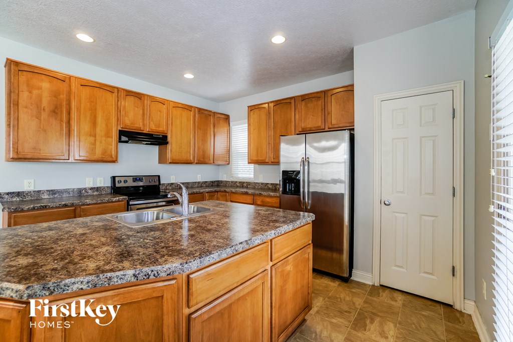 a kitchen with wooden cabinets and granite counter tops and a stainless steel refrigerator