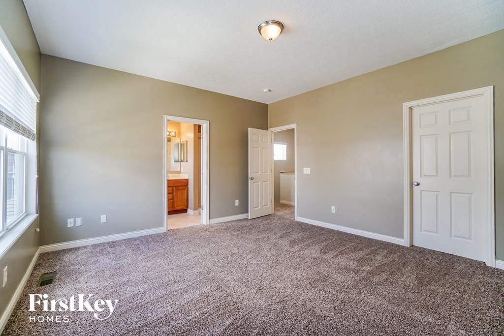 an empty living room with carpet and a door to a bathroom