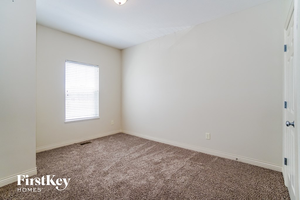 a bedroom with white walls and carpet and a window