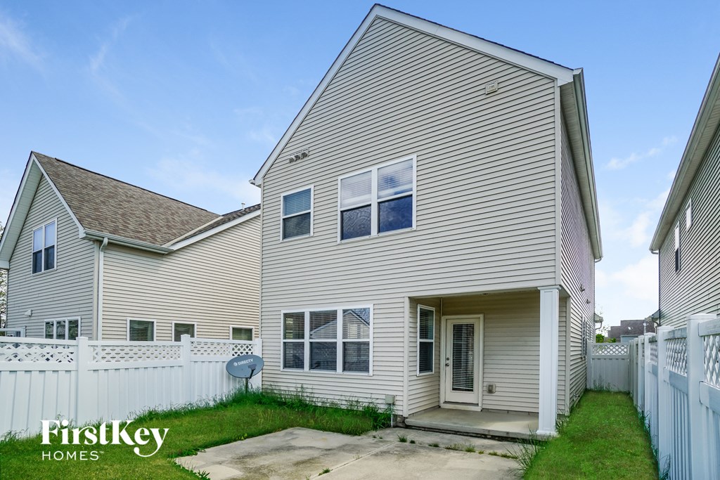 the outside of a house with a yard and a white fence