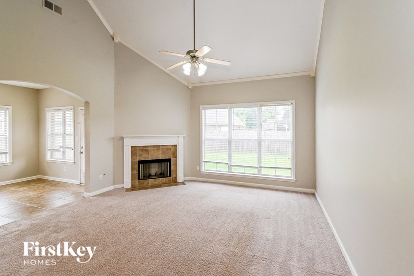 an empty living room with a fireplace and a ceiling fan