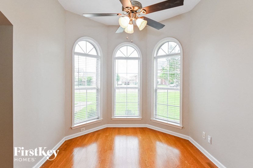an empty living room with three windows and a ceiling fan