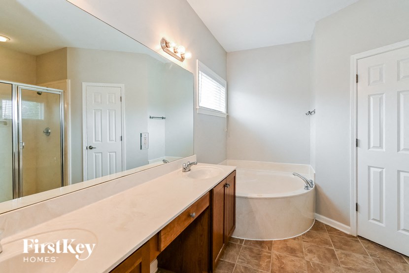 the master bathroom has a large tub and a large mirror