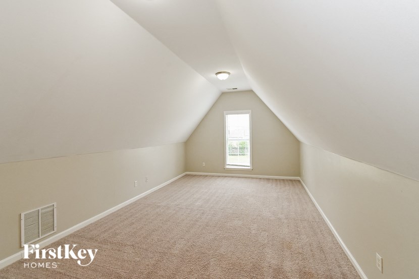a white attic room with a window and a carpet