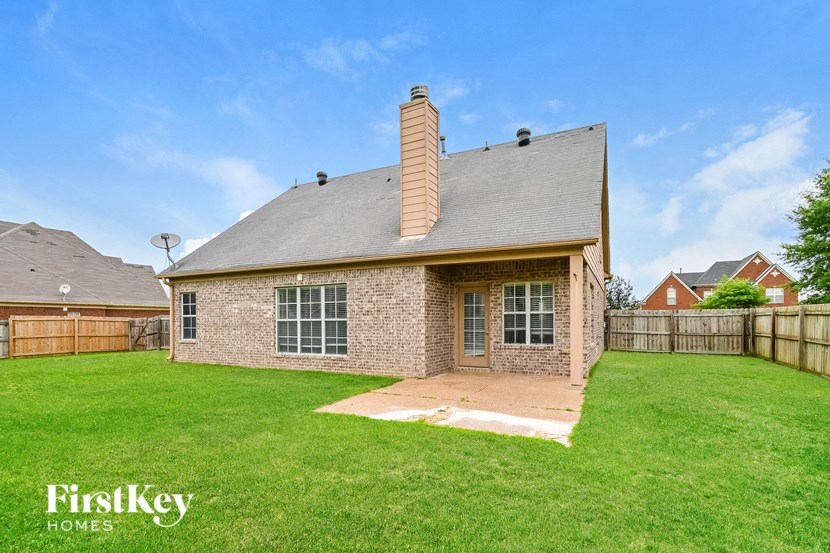 the backyard of a brick house with a lawn and a fence