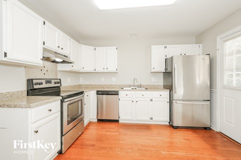 A kitchen with white cabinets and a stainless steel refrigerator.