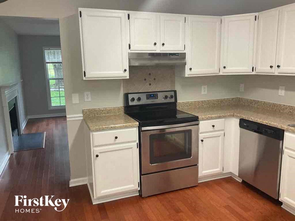 an empty kitchen with white cabinets and stainless steel appliances