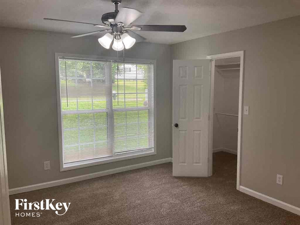 an empty bedroom with a ceiling fan and a window