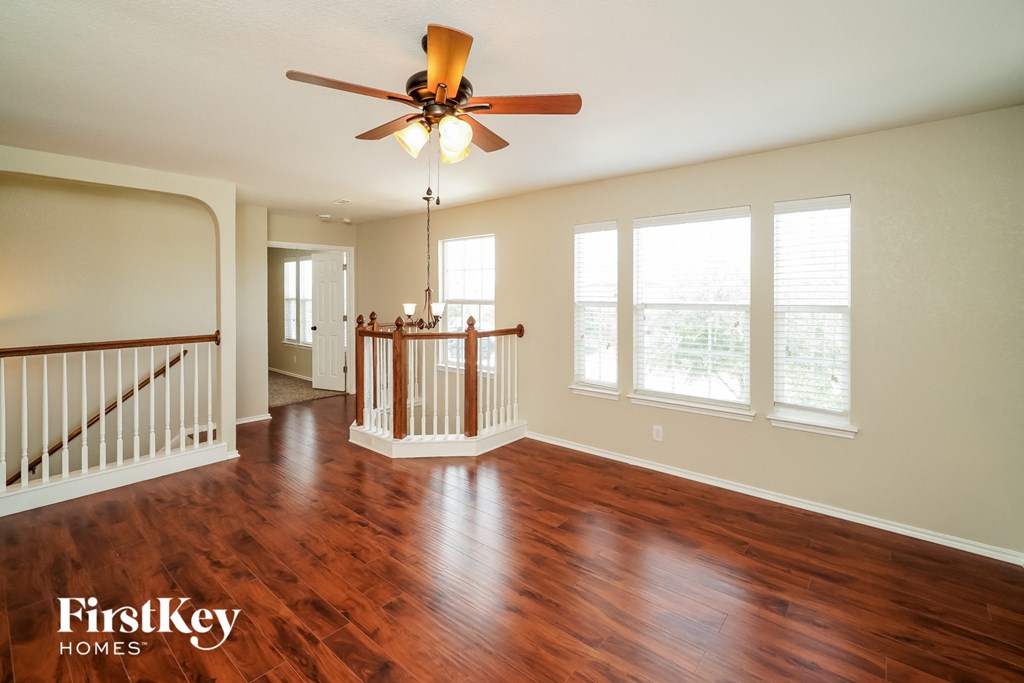 an empty living room with wood floors and a ceiling fan