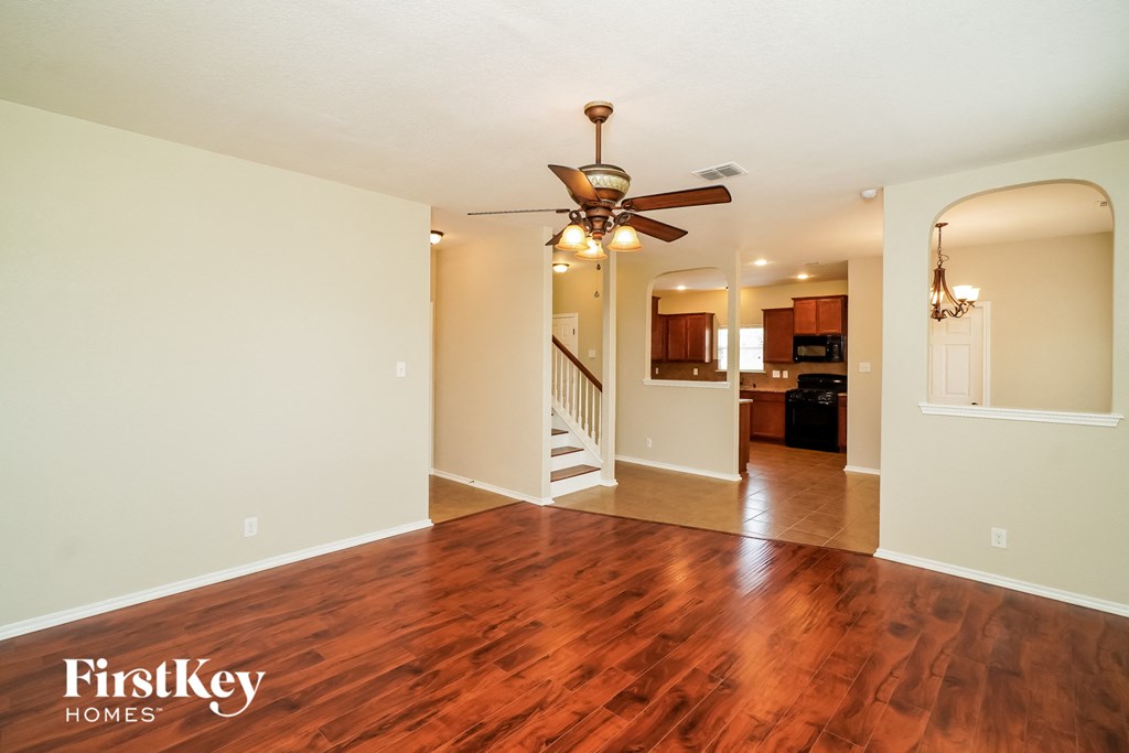 an empty living room with hard wood flooring and a ceiling fan