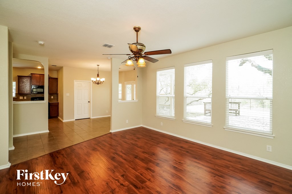 an empty living room with wood floors and a ceiling fan