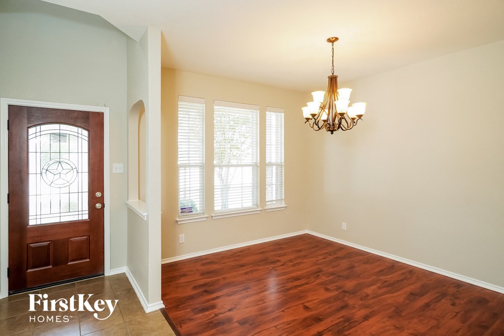 an empty dining room with wood flooring and a wooden door