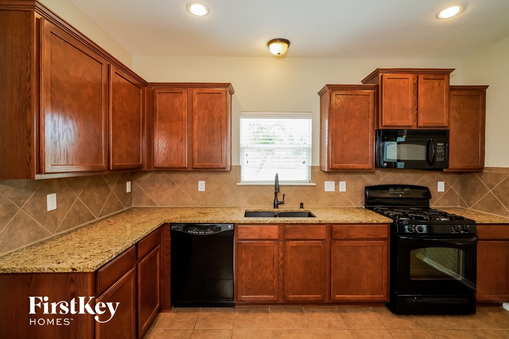 a kitchen with wood cabinets and black appliances and granite counter tops