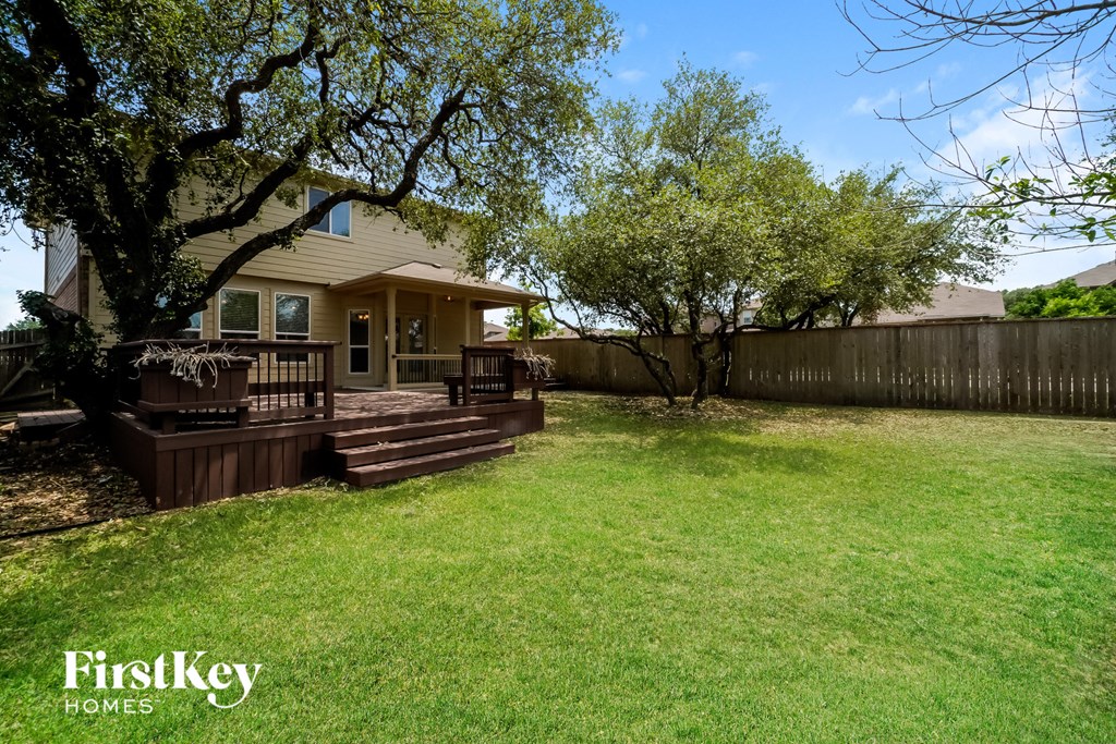 a backyard with a deck and trees and a house