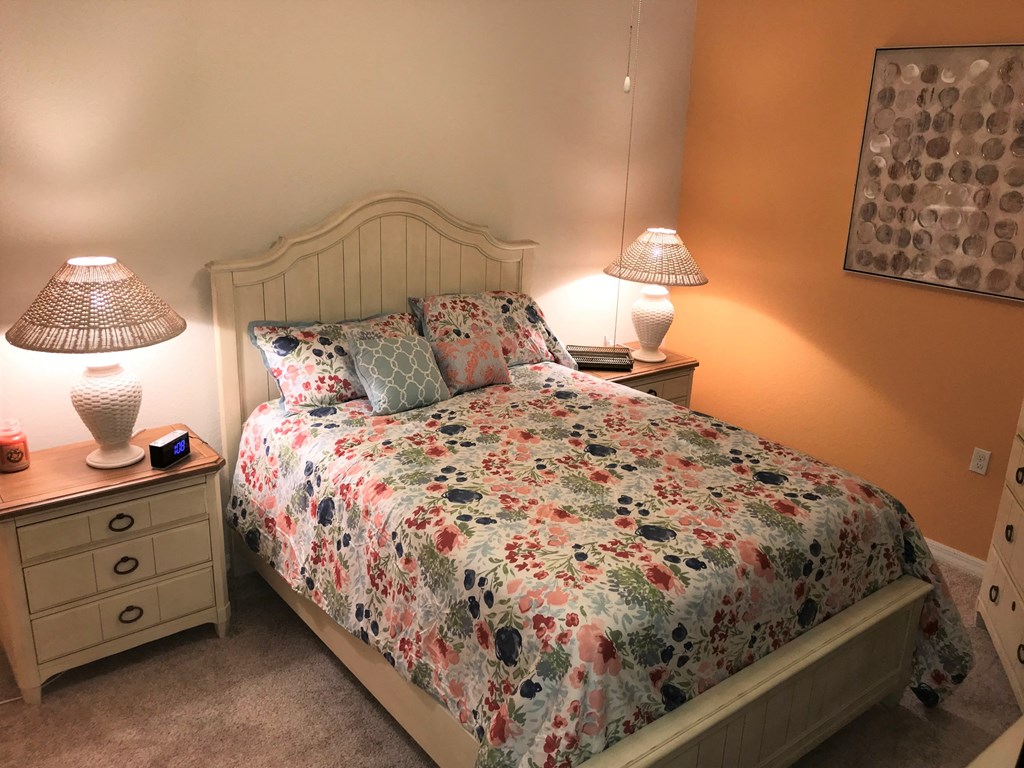A bedroom with a floral bedspread and two lamps.
