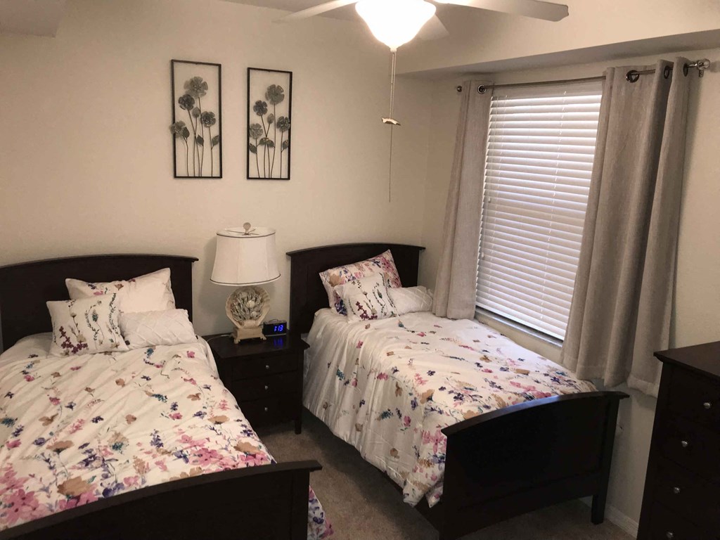 Two beds with floral bedspreads in a room with white walls.