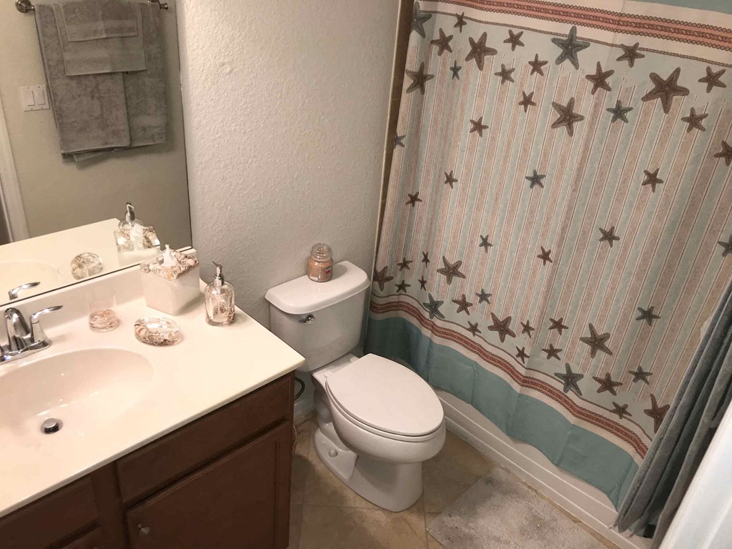 A bathroom with a toilet, sink, and shower curtain.