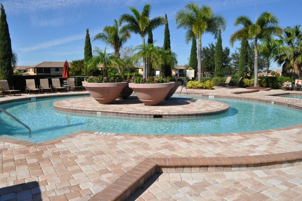 A pool surrounded by palm trees and a brick patio.