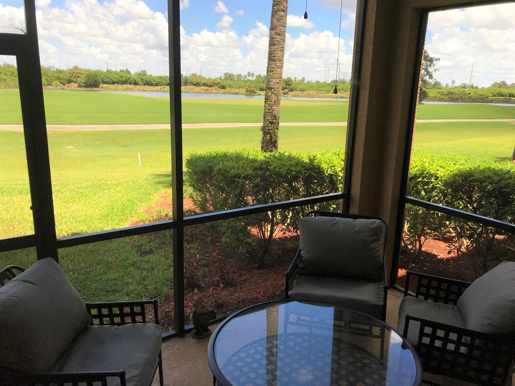 A patio with a table and chairs overlooking a field.