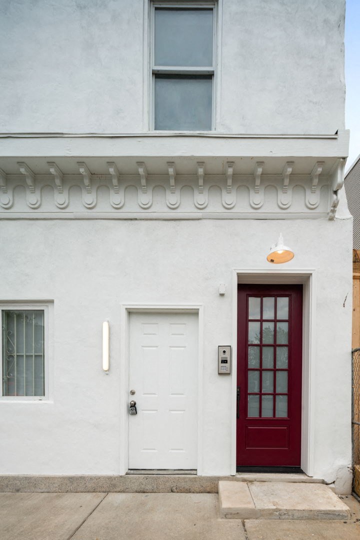 the front of a white house with a red door