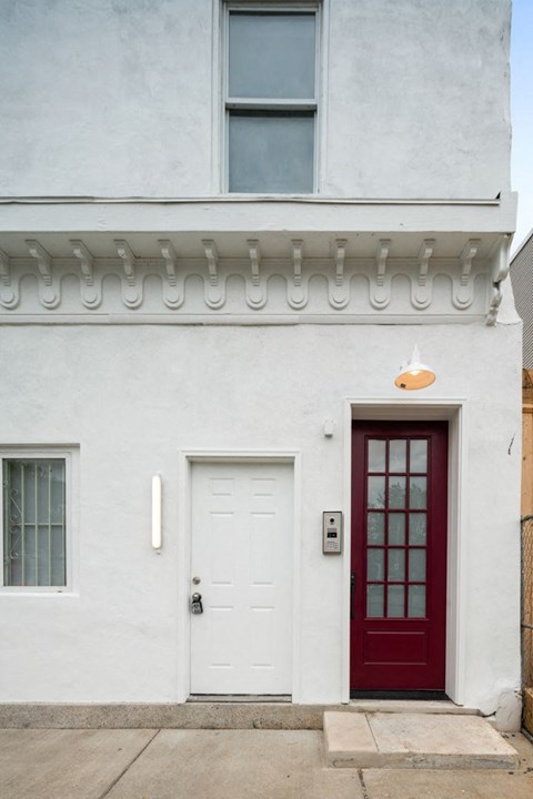 the front of a white house with a red door