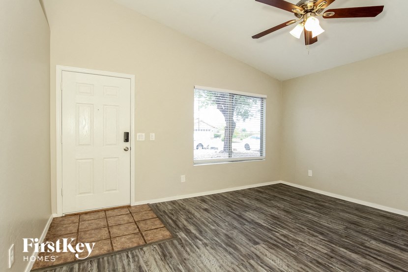 an empty living room with a ceiling fan and a window