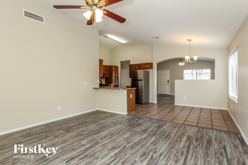 an empty living room with a ceiling fan and a kitchen
