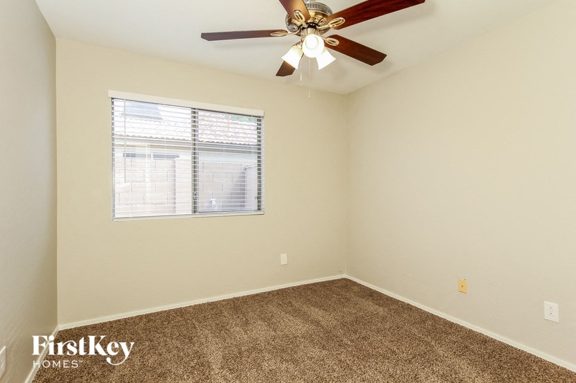 an empty room with a ceiling fan and a window