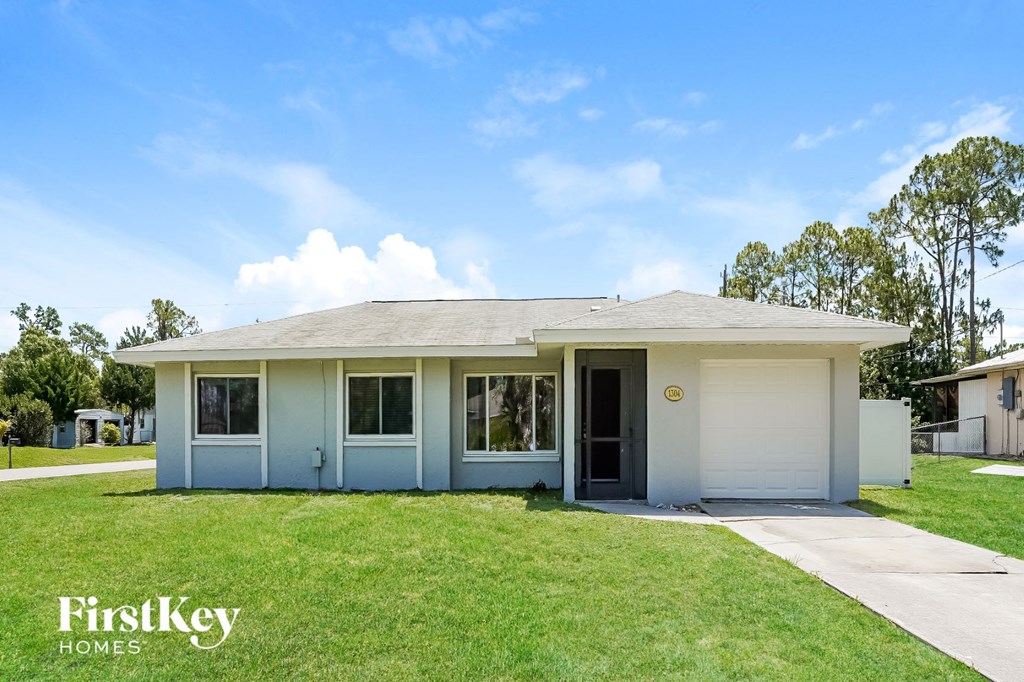 a small blue house with a lawn and a sidewalk