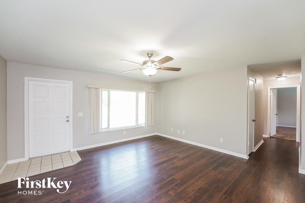an empty living room with wood floors and a ceiling fan