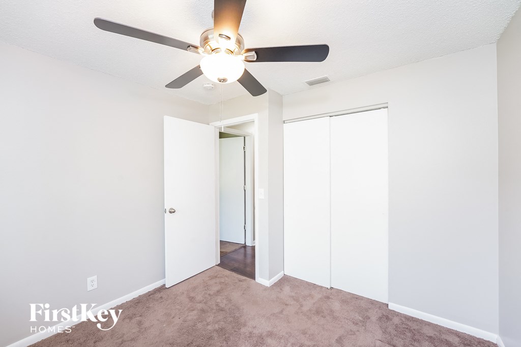 a bedroom with a ceiling fan and a closet