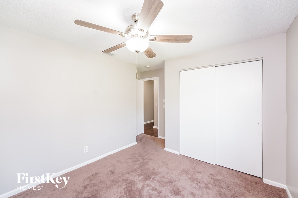 a bedroom with carpet and a ceiling fan and a closet