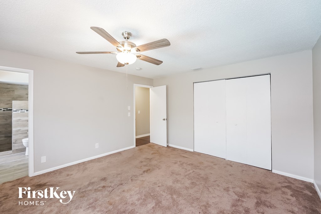 an empty living room with a ceiling fan and a closet