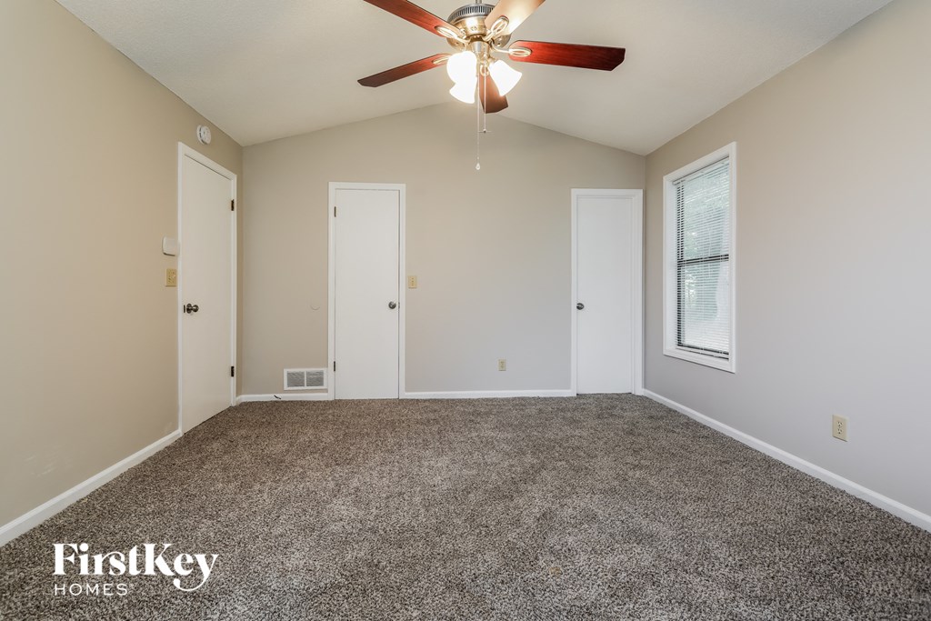 the master bedroom has a carpeted floor and a ceiling fan