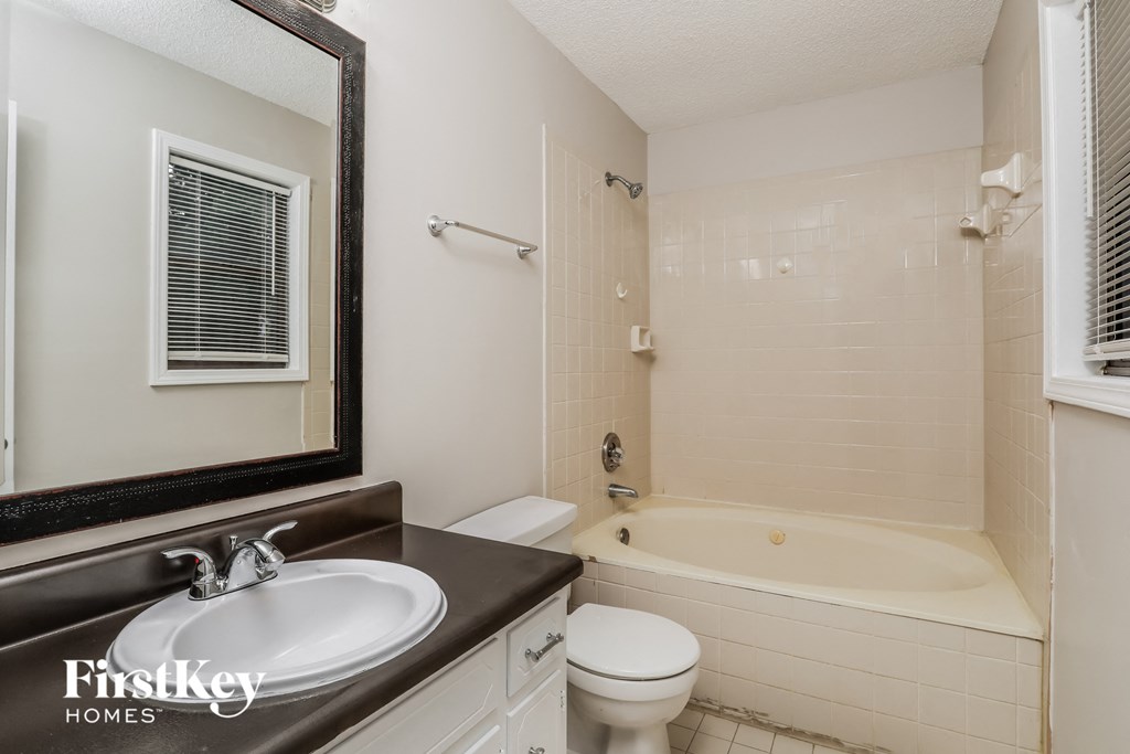 a bathroom with a sink toilet and bath tub and a mirror